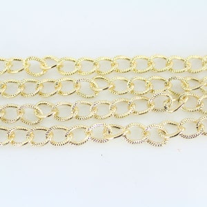 May include: Gold chain with a textured oval link design.