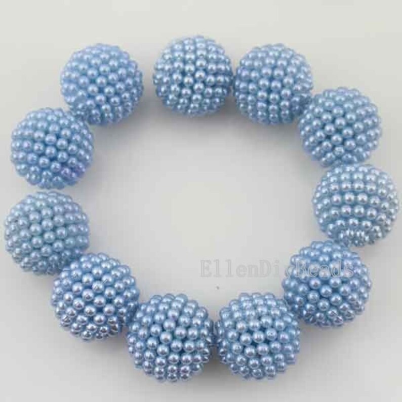 May include: A strand of light blue pearl beads, each bead is a sphere covered in smaller pearls. The beads are arranged in a circle.