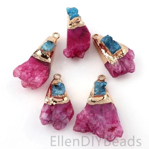 May include: Five pink and blue crystal pendant charms with gold accents. The charms are shaped like irregular crystals with a flat back and a loop for hanging.
