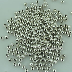 Pode incluir: Um grande monte de contas redondas prateadas. As contas são lisas e brilhantes.