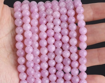 Puede incluir: Una hebra de cuentas redondas de color rosa pálido, probablemente hechas de piedra preciosa o vidrio, con un acabado liso y pulido. Las cuentas están enhebradas en un hilo transparente y tienen un diámetro aproximado de 6 mm.