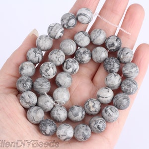 May include: A strand of gray and black marbled round beads. The beads are approximately 10mm in diameter.