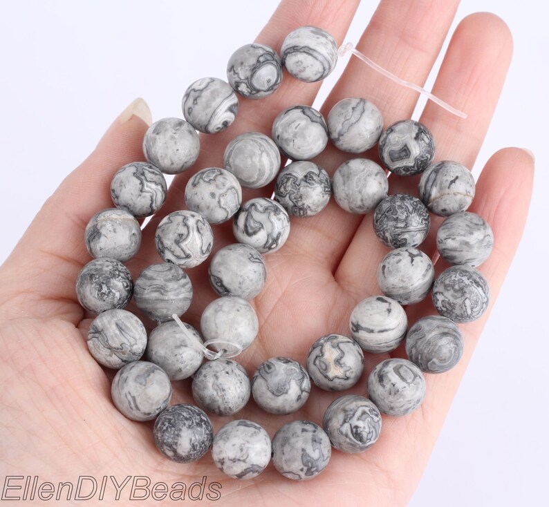 May include: A strand of gray and black marbled round beads. The beads are approximately 10mm in diameter.