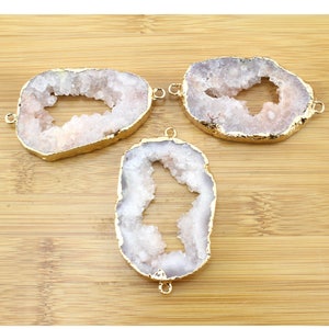May include: Three white agate slices with gold-toned metal accents. The agate slices have a natural, irregular shape with a hole in the center.