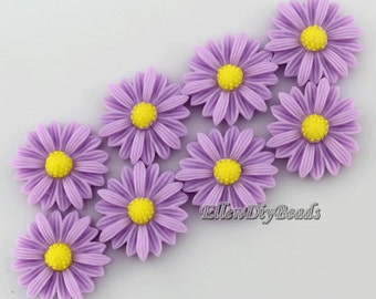May include: Eight purple daisy-shaped resin cabochons with yellow centers. The cabochons are arranged in a diagonal line on a white background.