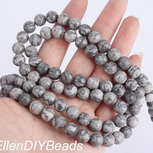 May include: A strand of gray and black marbled round beads. The beads are approximately 10mm in diameter.
