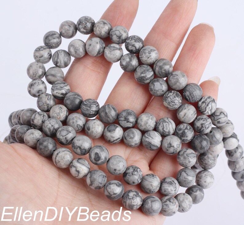 May include: A strand of gray and black marbled round beads. The beads are approximately 10mm in diameter.