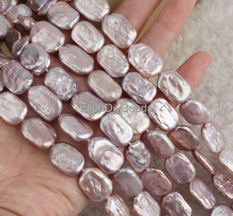 May include: A strand of pale lavender baroque freshwater pearls, each pearl is a unique oval shape with an iridescent sheen.