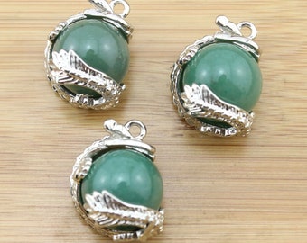 Puede incluir: Tres colgantes de piedra preciosa de aventurina verde con engastes de plata en forma de dragón. Cada colgante presenta una piedra verde redonda rodeada de un diseño de dragón de plata detallado.