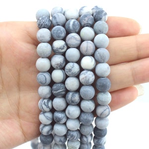 May include: A strand of grey and white marbled stone beads. The beads are round and have a smooth, polished finish.
