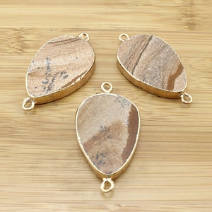 May include: Three brown and gold teardrop-shaped pendants with a gold metal bail. The pendants are made of a natural stone with a marbled pattern.