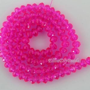 May include: A strand of bright pink faceted beads. The beads are strung together, forming a spiral shape. The beads are a vibrant, translucent pink color, and the facets catch the light.