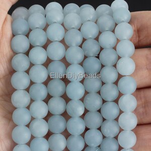 May include: A strand of light blue frosted round beads. The beads are approximately 8mm in diameter.