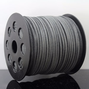 May include: A spool of grey suede cord, wound around a black plastic spool with a hole in the centre.