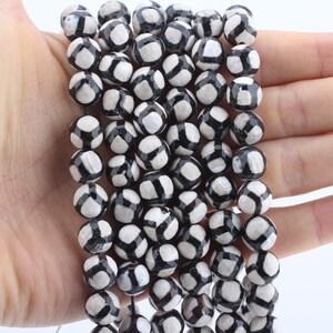 May include: A strand of black and white agate beads. The beads are round and have a faceted, geometric pattern.