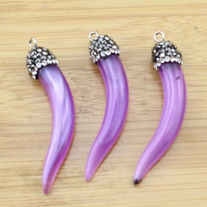 May include: Three purple resin tooth-shaped charms with silver-toned metal accents and clear rhinestone embellishments. Each charm has a loop for attaching to jewelry.
