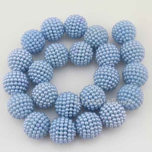 May include: A strand of light blue pearl beads, each bead is a sphere covered in smaller pearls. The beads are arranged in a circle, with some beads overlapping.