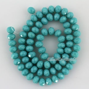 May include: A strand of turquoise blue faceted glass beads. The beads are round and have a smooth, polished finish.
