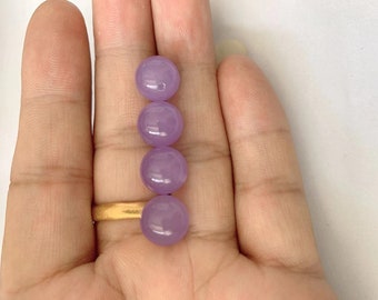 May include: Four round, lavender-colored beads, arranged vertically on a hand.