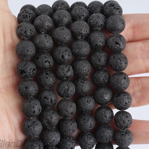 Peut inclure: Un brin de perles en lave noire. Les perles sont rondes et ont une surface rugueuse et texturée.