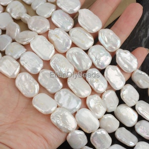May include: A strand of white baroque freshwater pearls, each pearl is oval shaped and has an iridescent sheen. The pearls are strung on a clear thread and are approximately 10mm in size.