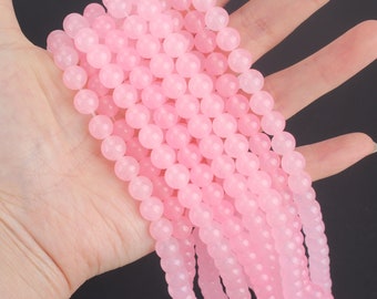Puede incluir: Una hebra de cuentas redondas de color rosa hechas de piedra natural. Las cuentas son lisas y pulidas, y tienen un color rosa claro.