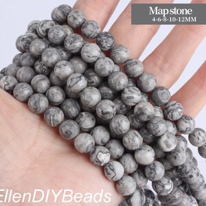 May include: A strand of gray and white marbled round beads. The beads are various sizes, ranging from 4 to 12 millimeters. The beads are called Mapstone.