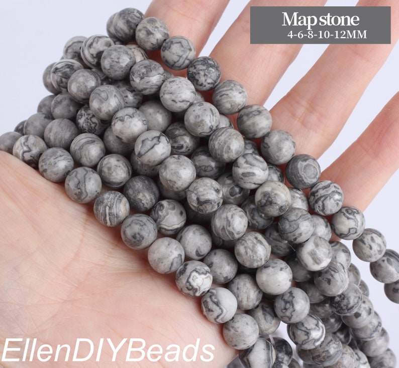 May include: A strand of gray and white marbled round beads. The beads are various sizes, ranging from 4 to 12 millimeters. The beads are called Mapstone.