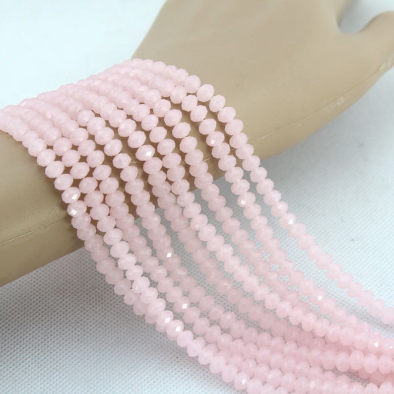 Puede incluir: Una hebra de cuentas de cristal facetadas de color rosa p&aacute;lido. Las cuentas son peque&ntilde;as y redondas, y est&aacute;n enhebradas en un hilo transparente.