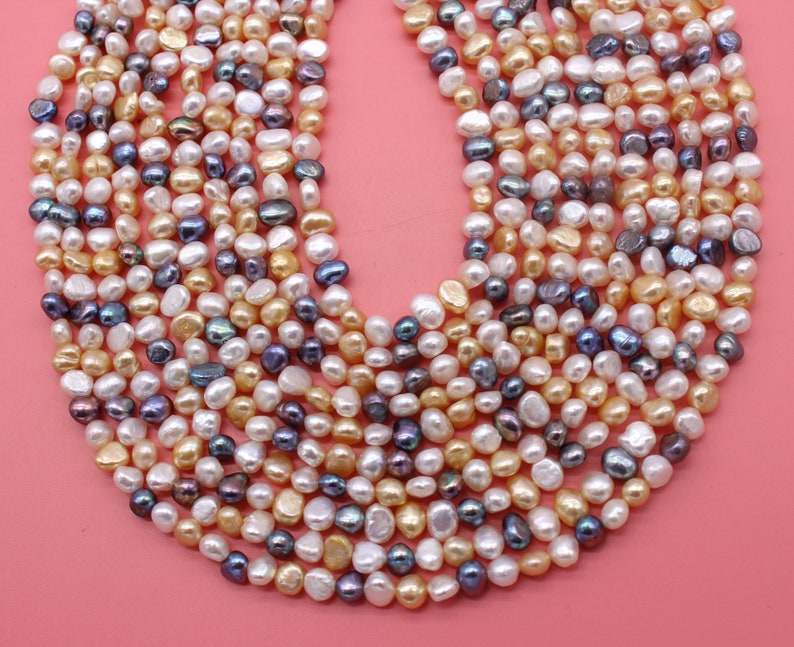 May include: A strand of freshwater pearls in a variety of colors, including white, cream, and purple. The pearls are irregular in shape and have a smooth, lustrous finish.