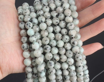Puede incluir: Una hebra de cuentas redondas de piedra preciosa verde y negra moteadas. Las cuentas tienen aproximadamente 6 mm de diámetro y tienen un acabado liso y pulido.