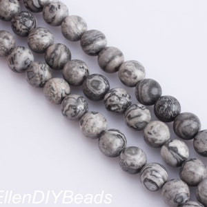May include: A strand of gray and black marbled round beads. The beads are smooth and have a natural, polished look.