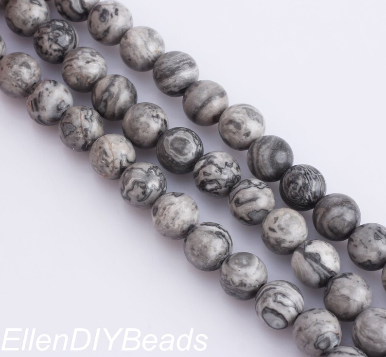 May include: A strand of gray and black marbled round beads. The beads are smooth and have a natural, polished look.