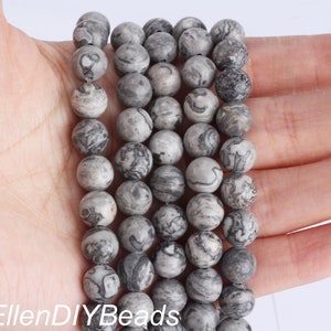 May include: A strand of gray and black marbled round beads. The beads are approximately 8mm in diameter and have a smooth, polished finish.