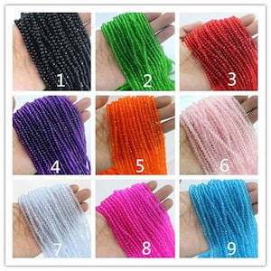 May include: Nine strands of faceted glass beads in various colors, including black, green, red, purple, orange, pink, white, hot pink, and blue. Each strand is held in a hand and numbered 1 through 9.
