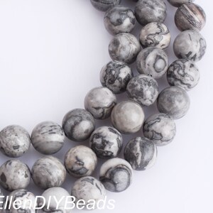 May include: A strand of gray and black marbled round beads. The beads are approximately 10mm in diameter.