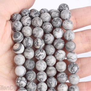 May include: A strand of gray and white marbled round beads. The beads are approximately 10mm in diameter and have a smooth, polished finish.
