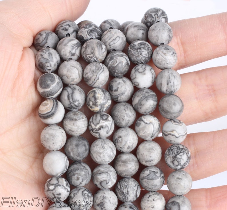 May include: A strand of gray and white marbled round beads. The beads are approximately 10mm in diameter and have a smooth, polished finish.