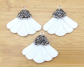 May include: Three white shell flower charms with a silver tone metal top adorned with black and clear rhinestones.