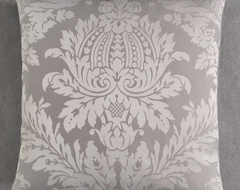 May include: A gray throw pillow with a white damask pattern. The pattern features a large, ornate floral design.