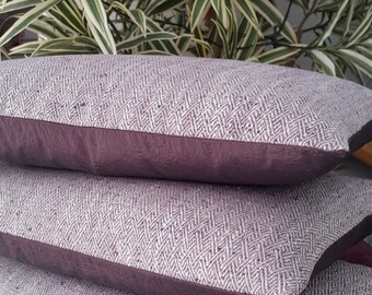 May include: Two purple and white patterned throw pillows with a dark purple border. The pillows are stacked on top of each other.
