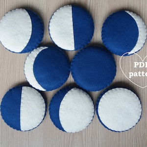 Puede incluir: Ocho piezas circulares de fieltro, cada una representando una fase lunar. El fieltro es azul oscuro y blanco. El texto "PDF pattern" es visible.