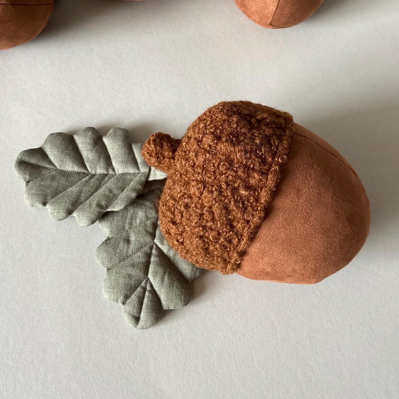 May include: A brown felt acorn with a fuzzy brown crocheted cap and two green felt leaves attached.