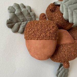 May include: A group of brown and tan acorn-shaped plush toys with fuzzy tops and fabric leaf accents.