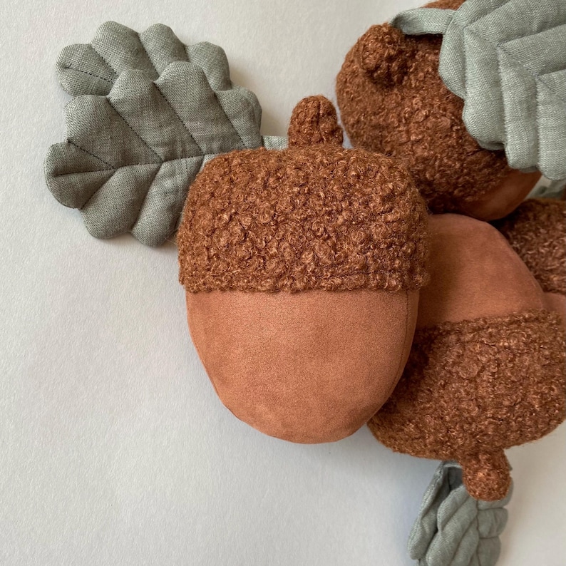 May include: A group of brown and tan acorn-shaped plush toys with fuzzy tops and fabric leaf accents.