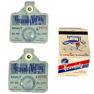 Può includere: Due biglietti vintage per gli impianti di risalita Heavenly Valley Lake Tahoe e un fiammifero. I biglietti sono azzurri con le parole "Heavenly Valley" e "Adult" stampate sopra. Il fiammifero ha un design rosso, bianco e blu con le parole "Heavenly".
