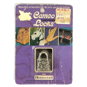 May include: A vintage Cameo Combination Locks package. The purple card features images of a handbag, a dog, a hand with a bracelet, and a jewelry box. A silver lock with a floral design is visible. The text reads "Beautiful protection for all your personal things."