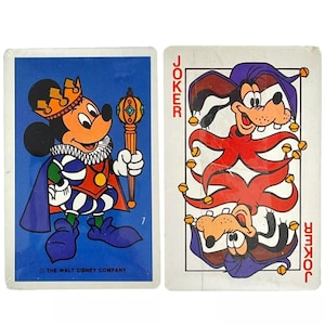 May include: Two playing cards featuring Disney characters. The first card is a blue background with Mickey Mouse dressed as a king holding a scepter. The second card is a white background with Goofy dressed as a jester. Both cards say "Joker" on them.