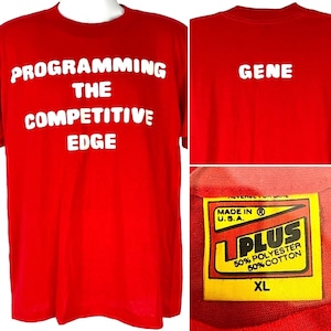 以下が含まれることがあります： 赤いTシャツに、白い文字で「Programming the Competitive Edge」と書いてあり、後ろには「Gene」と書いてあります。Tシャツには、黄色と黒のタグが付いていて、「L Plus 50% ポリエステル 50% コットン XL アメリカ製」と書いてあります。