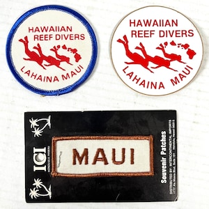 Peut inclure: Deux écussons ronds et un écusson rectangulaire. Les écussons ronds indiquent "HAWAIIAN REEF DIVERS LAHAINA MAUI" avec des figures rouges. L'écusson rectangulaire indique "MAUI" en lettres marron. Ce sont des souvenirs.